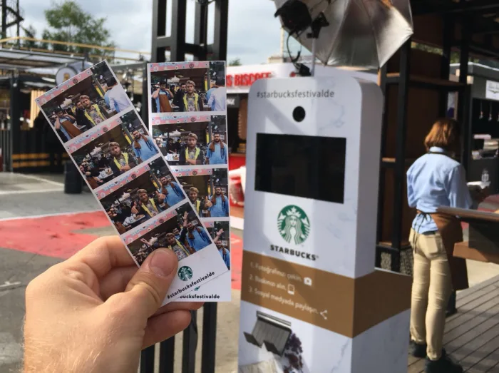 A guest holding photo strips at a Starbucks-branded photo booth